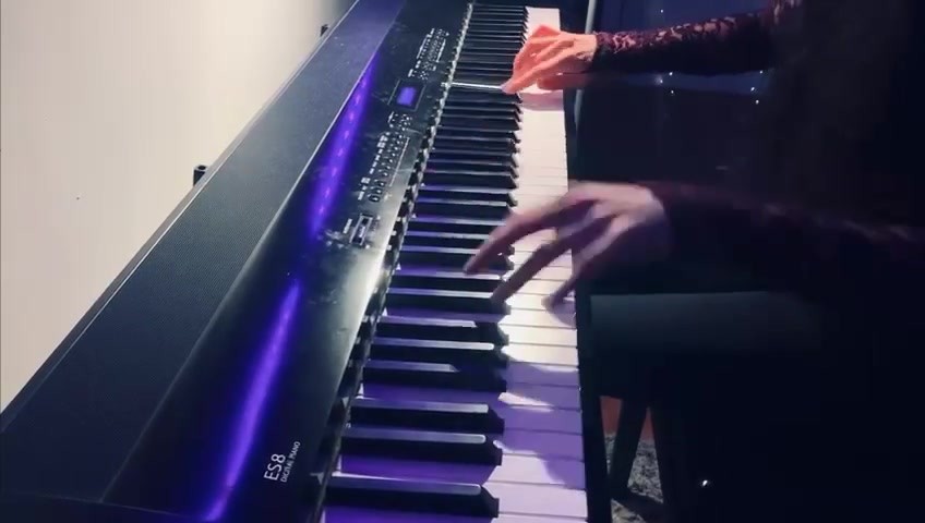 Mains jouant sur un piano numérique éclairé de violet, pour l’extrait du Prélude de Chopin.